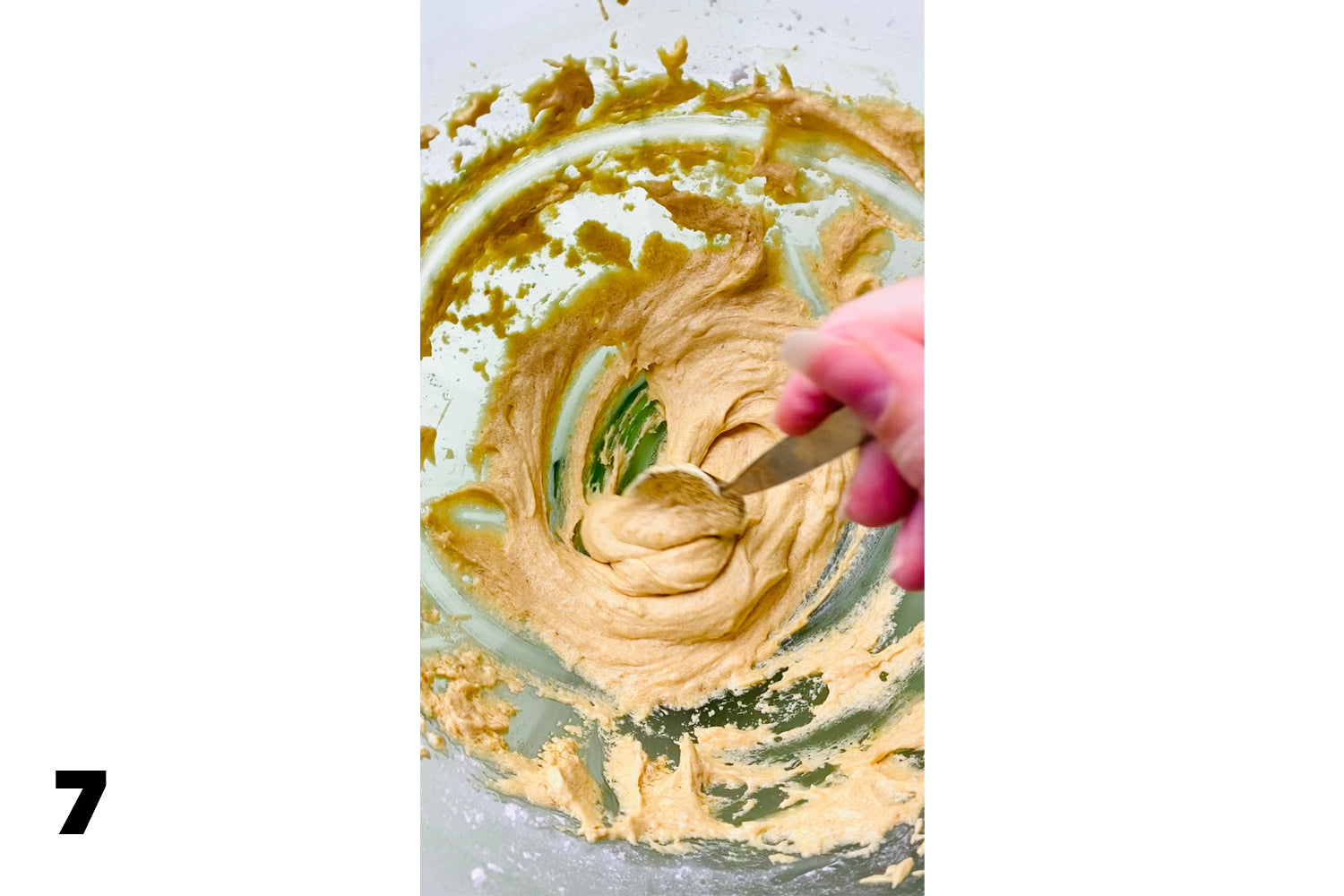 close up of hand stirring frosting with spoon