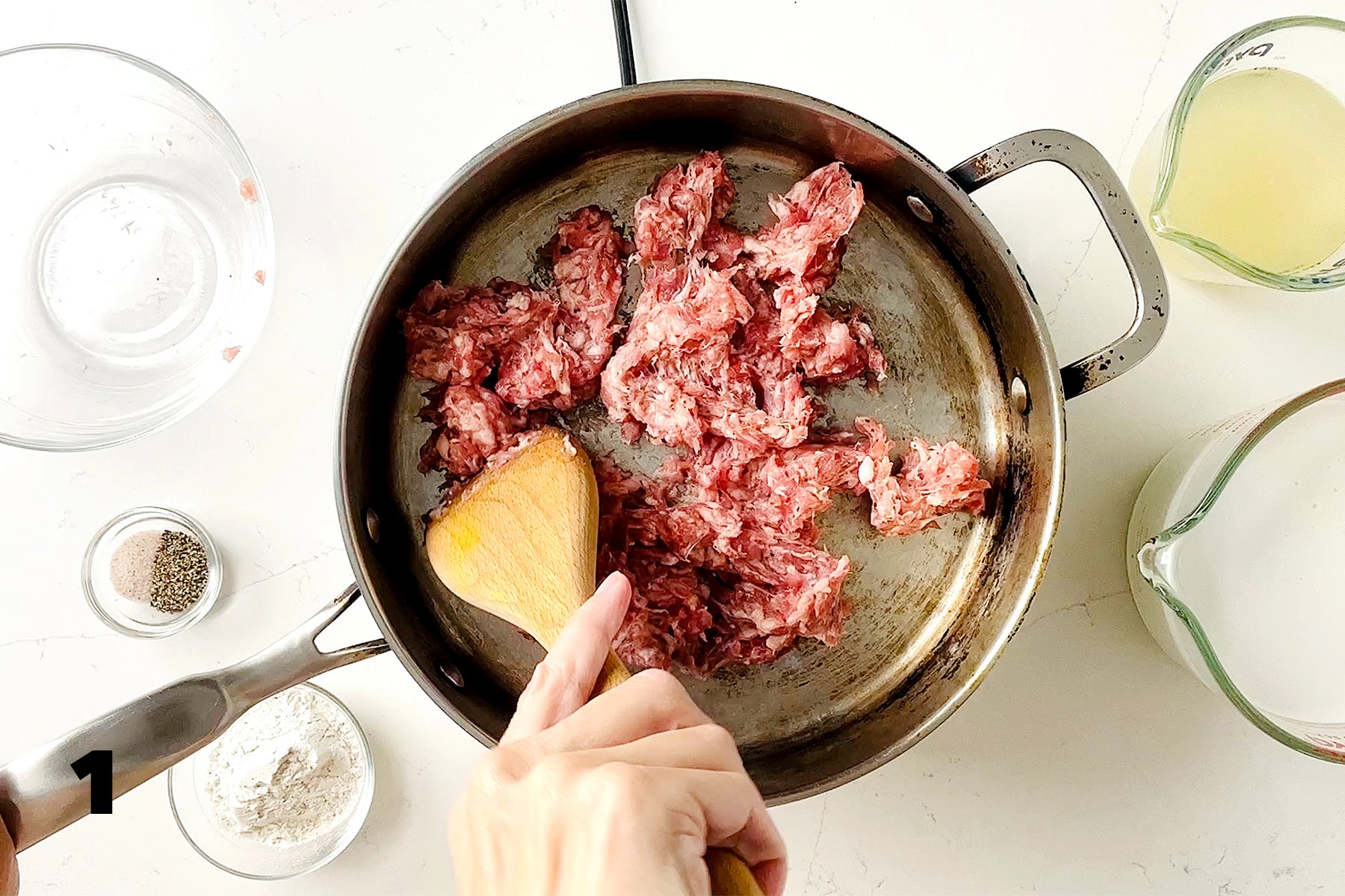 breaking up ground pork with wooden spoon in pan
