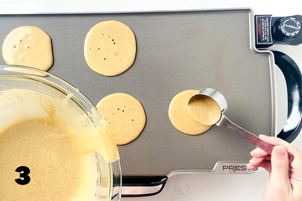 pouring batter into pan for pancakes