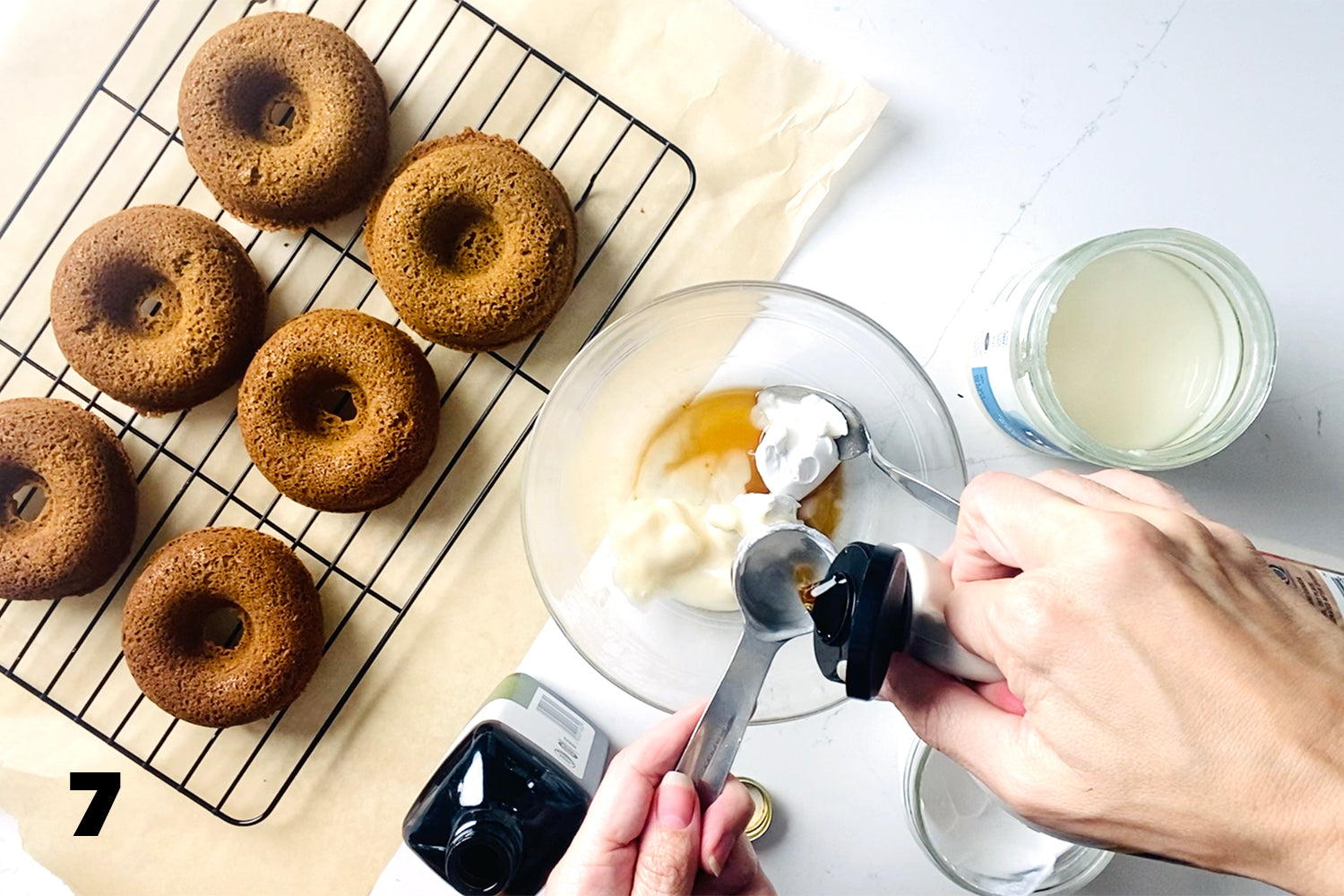 adding ingredients to glass bowl next to donuts on wire rack