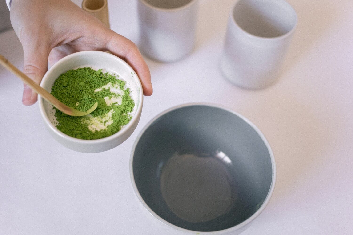 person holding a bowl of green kratom powder