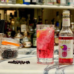 A bottle and glass of non alcoholic, vegan friendly pink gin and tonic in a cocktail bar, available for delivery from Barbury Hill 