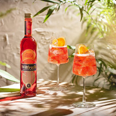 A bottle of Wilfred's vegan and non alcoholic spritz with two glasses garnished with a slice of orange, available for delivery from Barbury Hill  