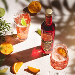 A bottle of Wilfred's vegan and non alcoholic spritz with two glasses garnished with a slice of orange, available for delivery from Barbury Hill