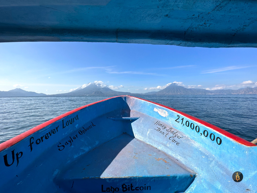 Photo taken from the inside of the Bitcoin boat showing the writings on the inside saying "21 million," "up forever laura," honeyb adger don't care," "saylor on board," and showing the surrounding views of the lake and the volcanos in Guatemala