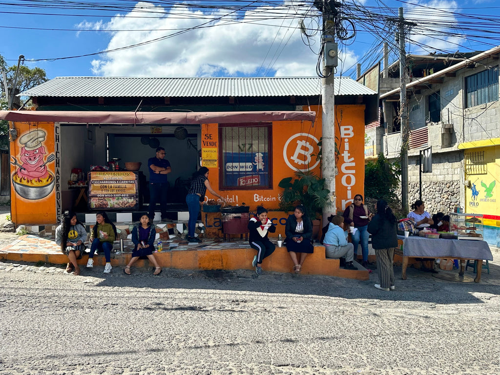 BBQ joint in Panajachel, also known as Bitcoin Lake, painted in orange with the Bitcoin szmbol on it and a lot of people sitting in front of the building