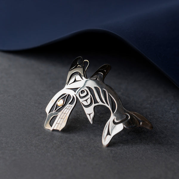 Silver Killer Whale pendant with laser cut details. Orca has a long, snubbed-nosed head, dorsal fin, pectoral fin, and a tail in this depiction.