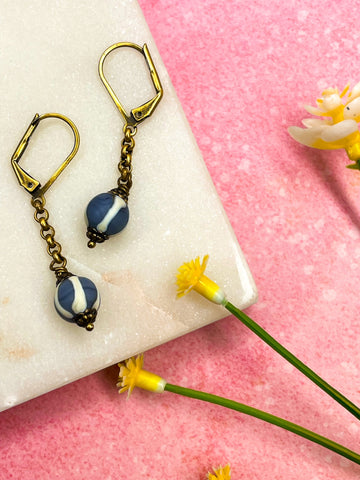 Brass drop earrings with blue and white striped glass ball.