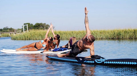 people doing yoga on paddle boards near ocean grass