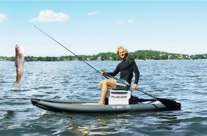 man with a fish on his pole while riding a paddle board