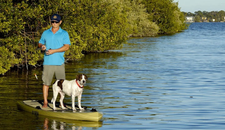 man and dog fishing on a paddle board