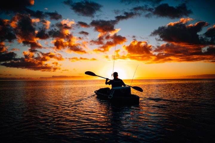 man paddling into the sunset