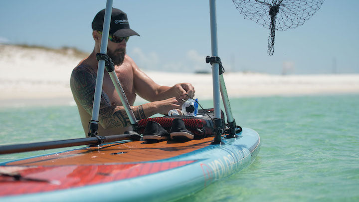 Man setting up fishing gear on a paddle board