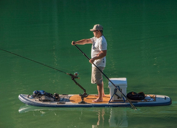 man fishing on paddle board in a lake