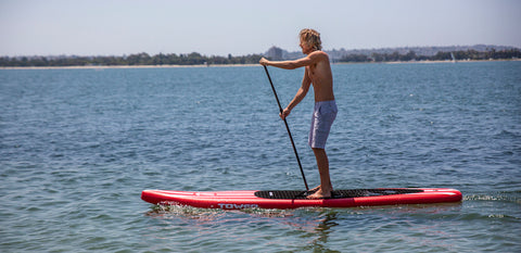 man riding on a red paddle board