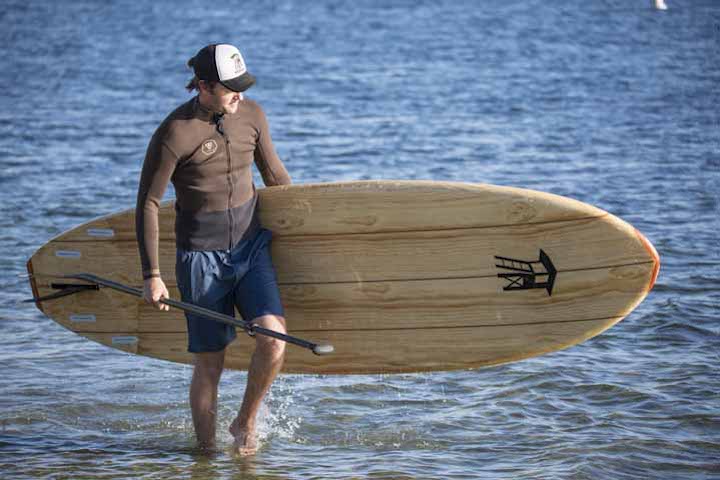 Man walking with a wood paddle board