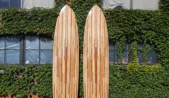 pair of wood paddle boards leaning against a bush