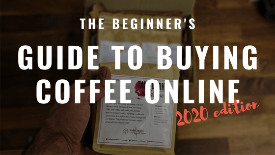 the beginner's guide to buying coffee online 2020 edition text overlay on a male hand holding coffee bag