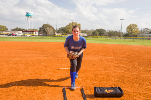 Softball pitcher in their windup about to pitch a ball during practive.