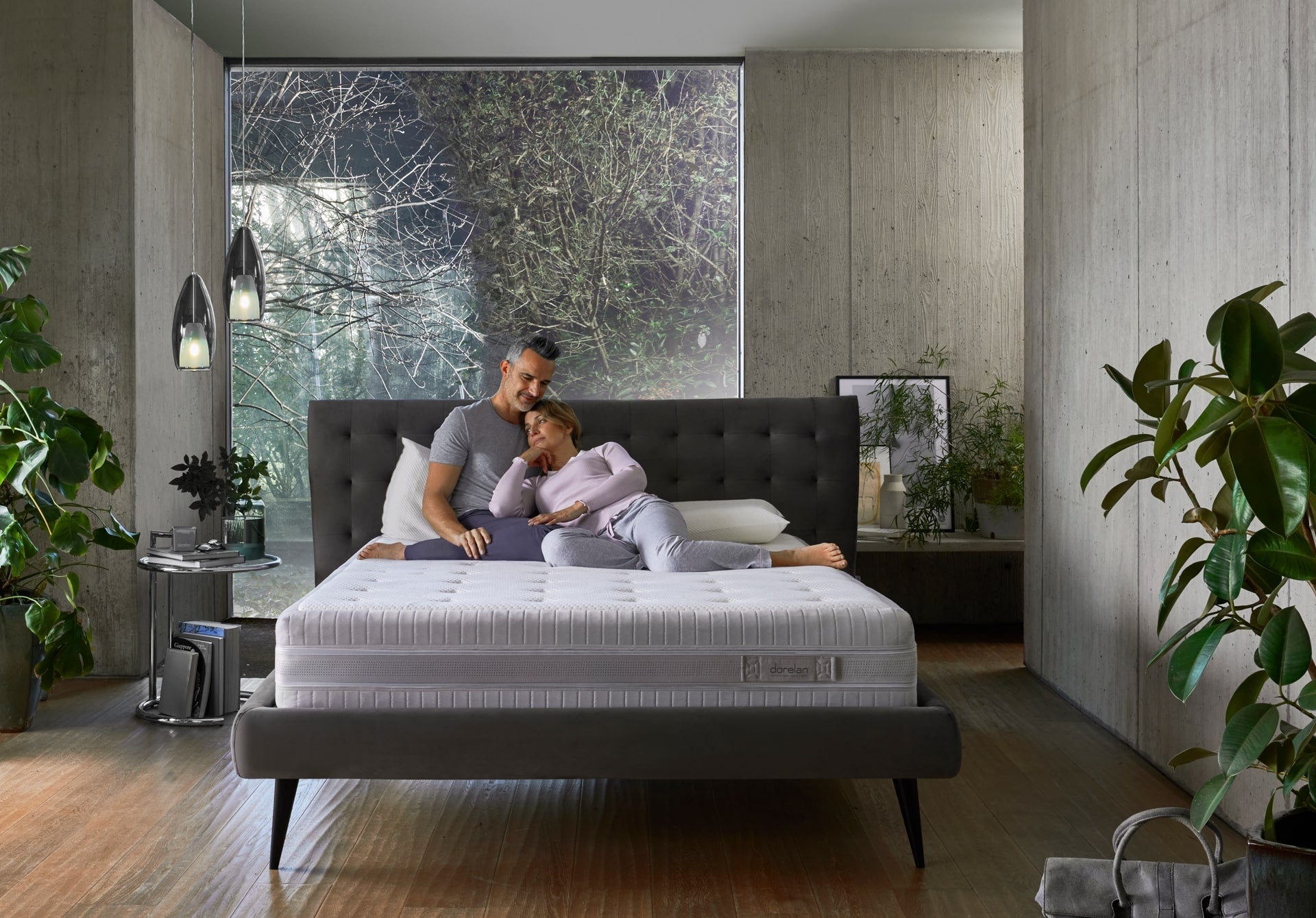 A couple in bed, the woman laying her back against the man's chest, both looking lovely.