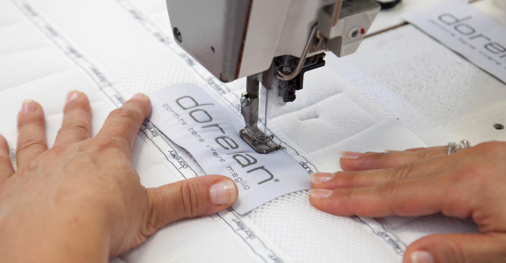 Hands attaching Dorelan label on custom mattress