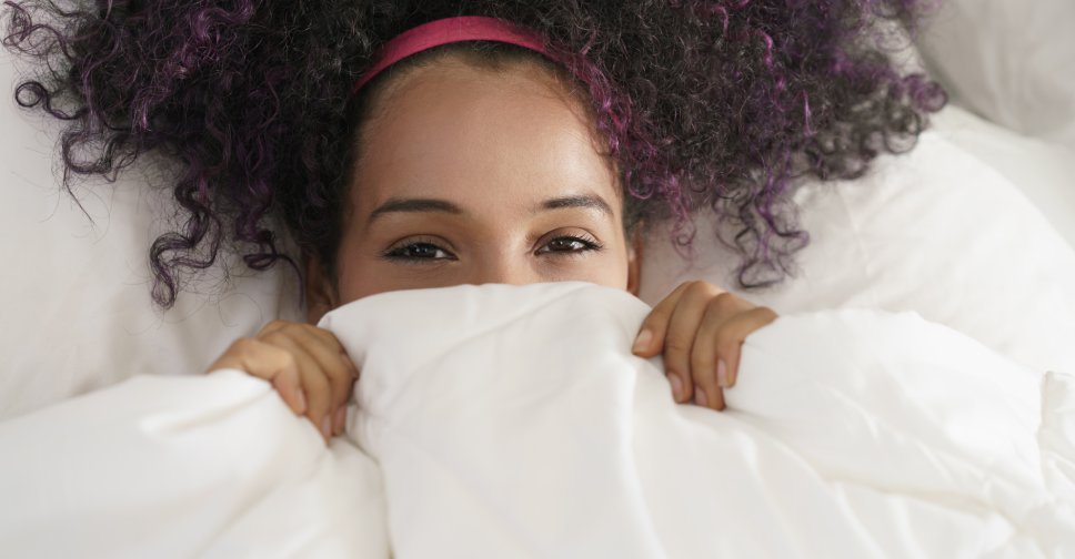 Close up of woman peeking over bedsheets