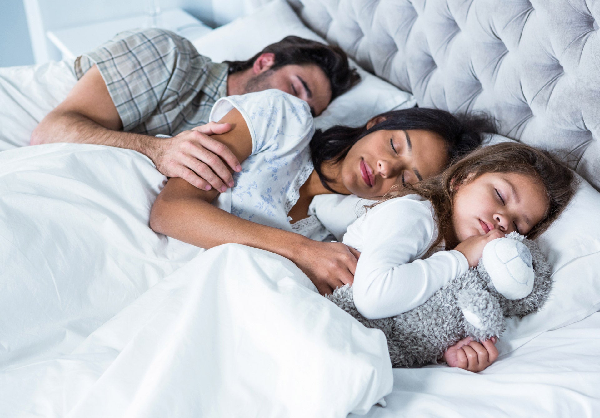 Mother, father and small child sleeping peacefully in the same bed