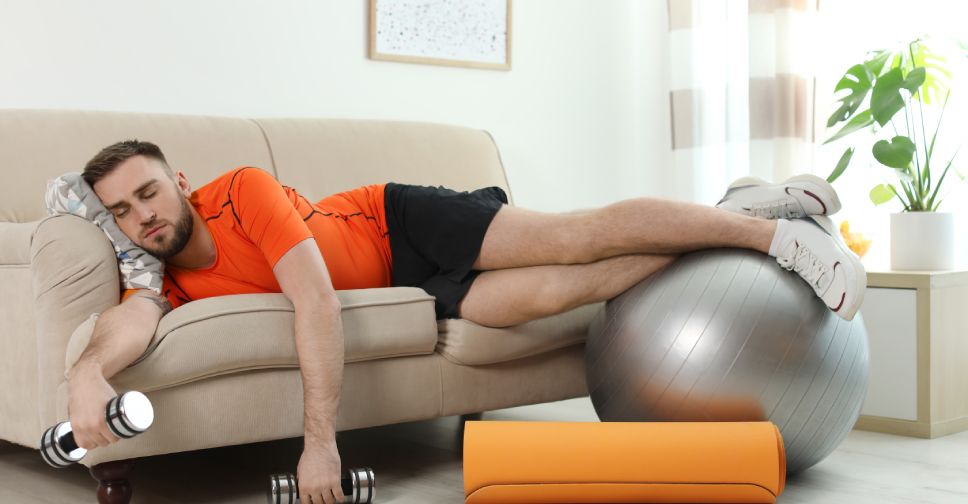 man lying on couch with a weight in his hand and legs on an exercise ball