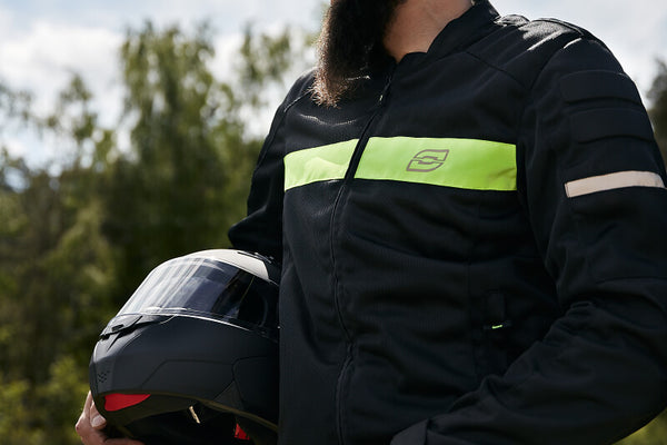 Mężczyzna trzymający kask w kurtce motocyklowej 