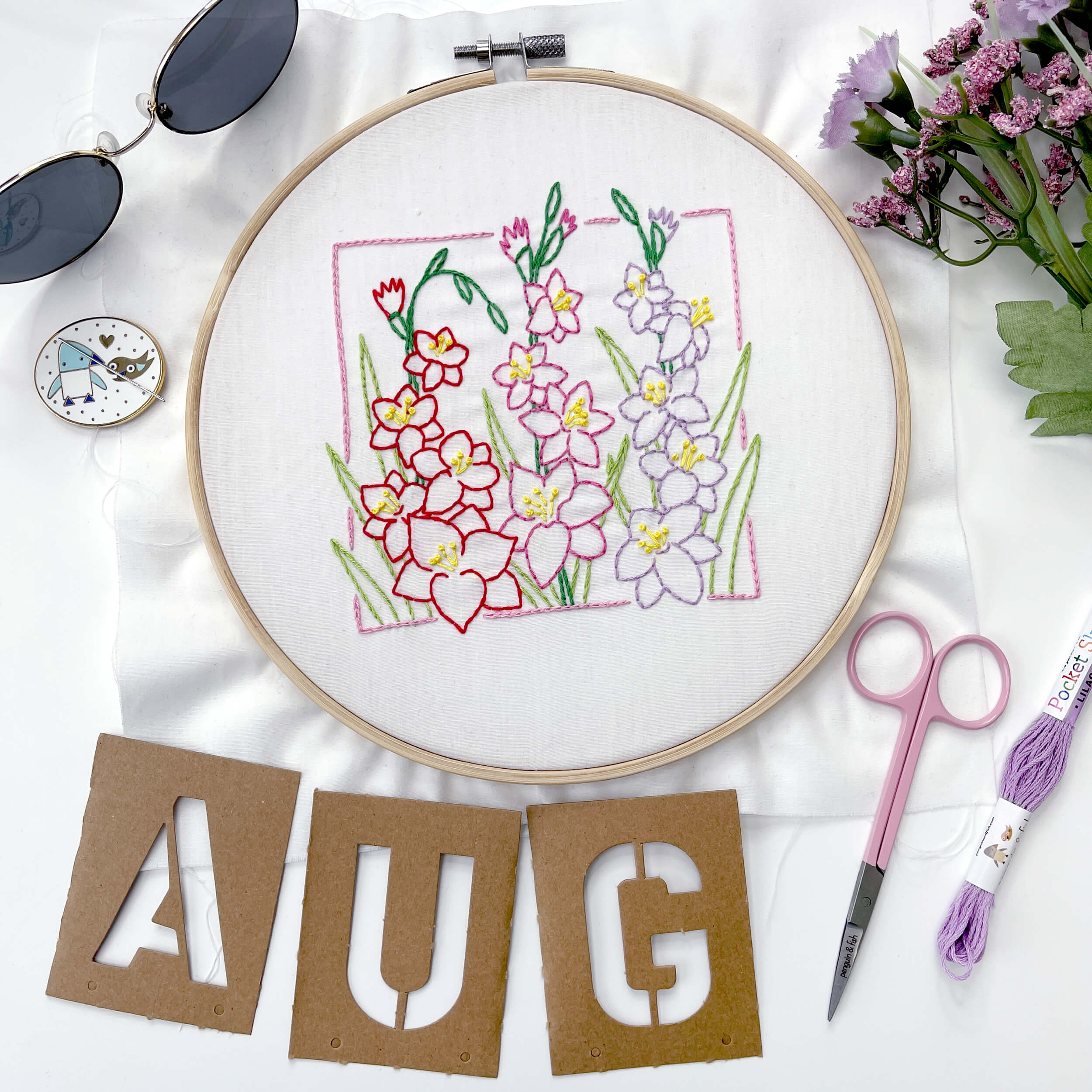 Finished August Gladiolus pattern with letters A.U.G. and purple embroidery scissors