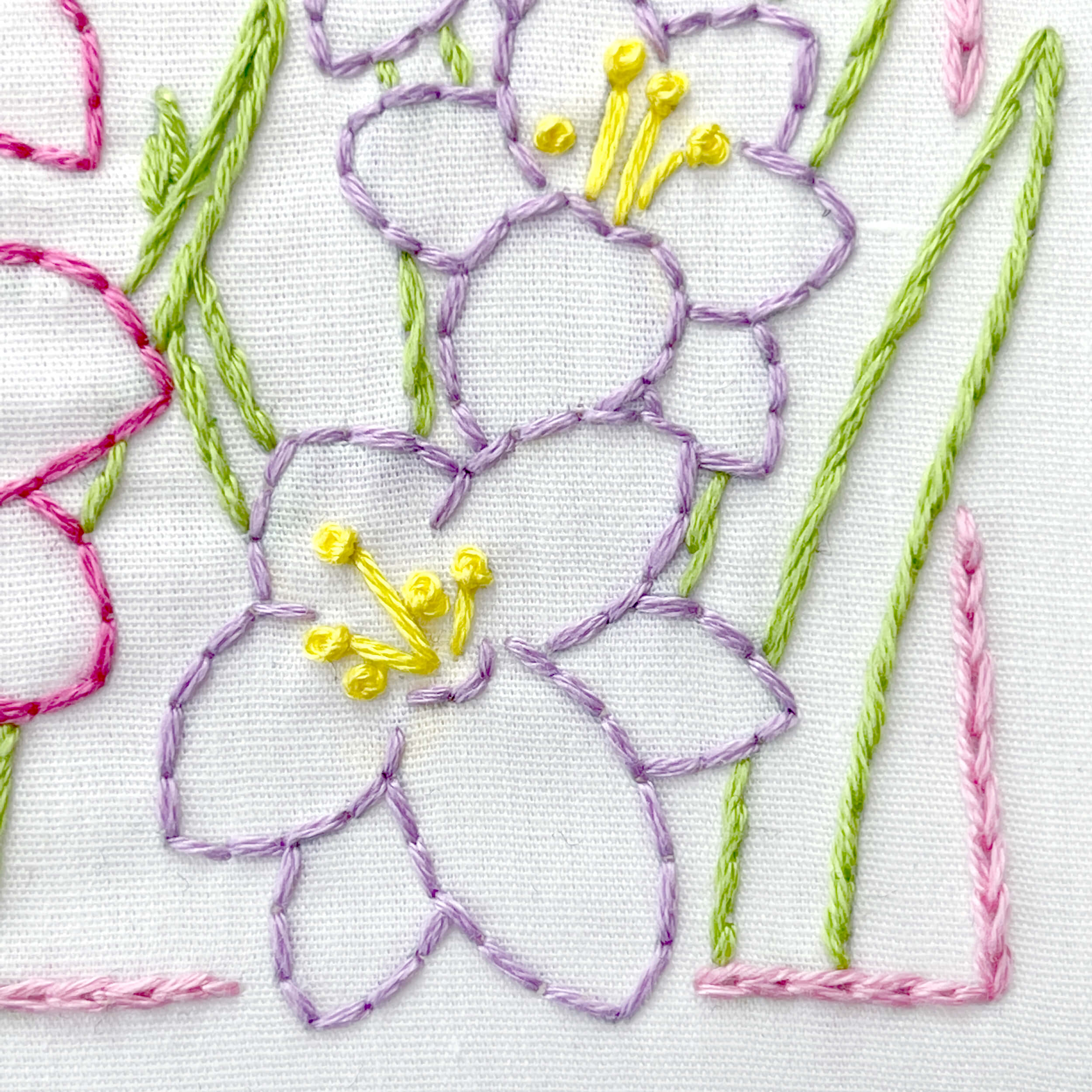 Close up of purple gladiolus embroidery flowers with yellow french knots in the center