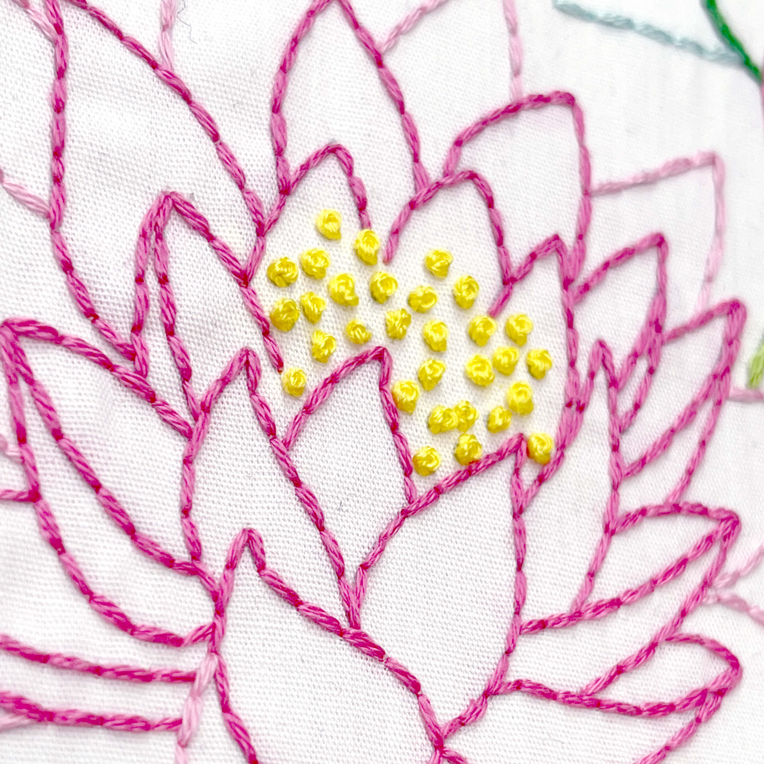 Dark pink embroidered water lily with yellow french knots in the center