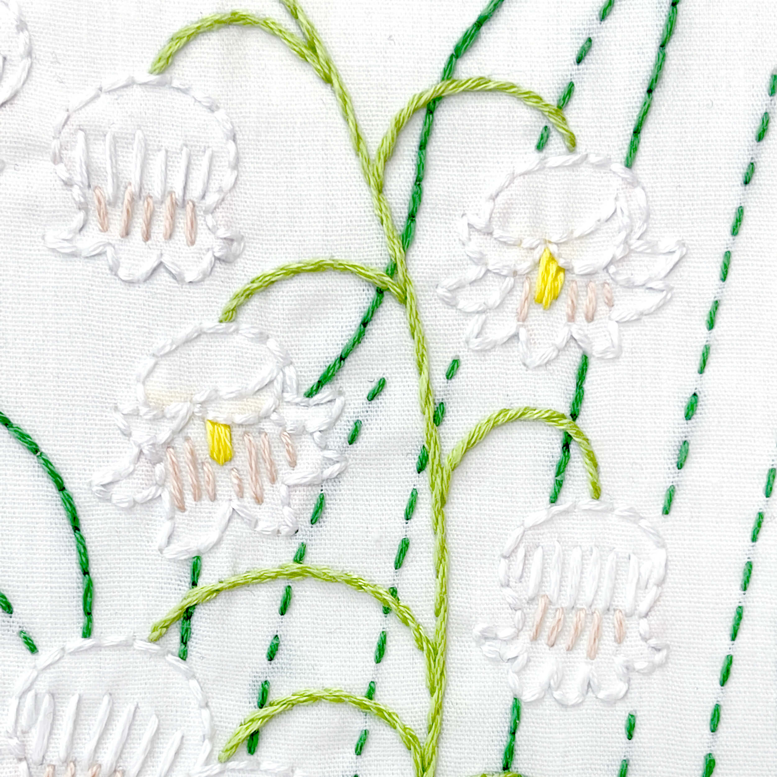 Close up of lily of the valley embroidery flowers in white with yellow centers