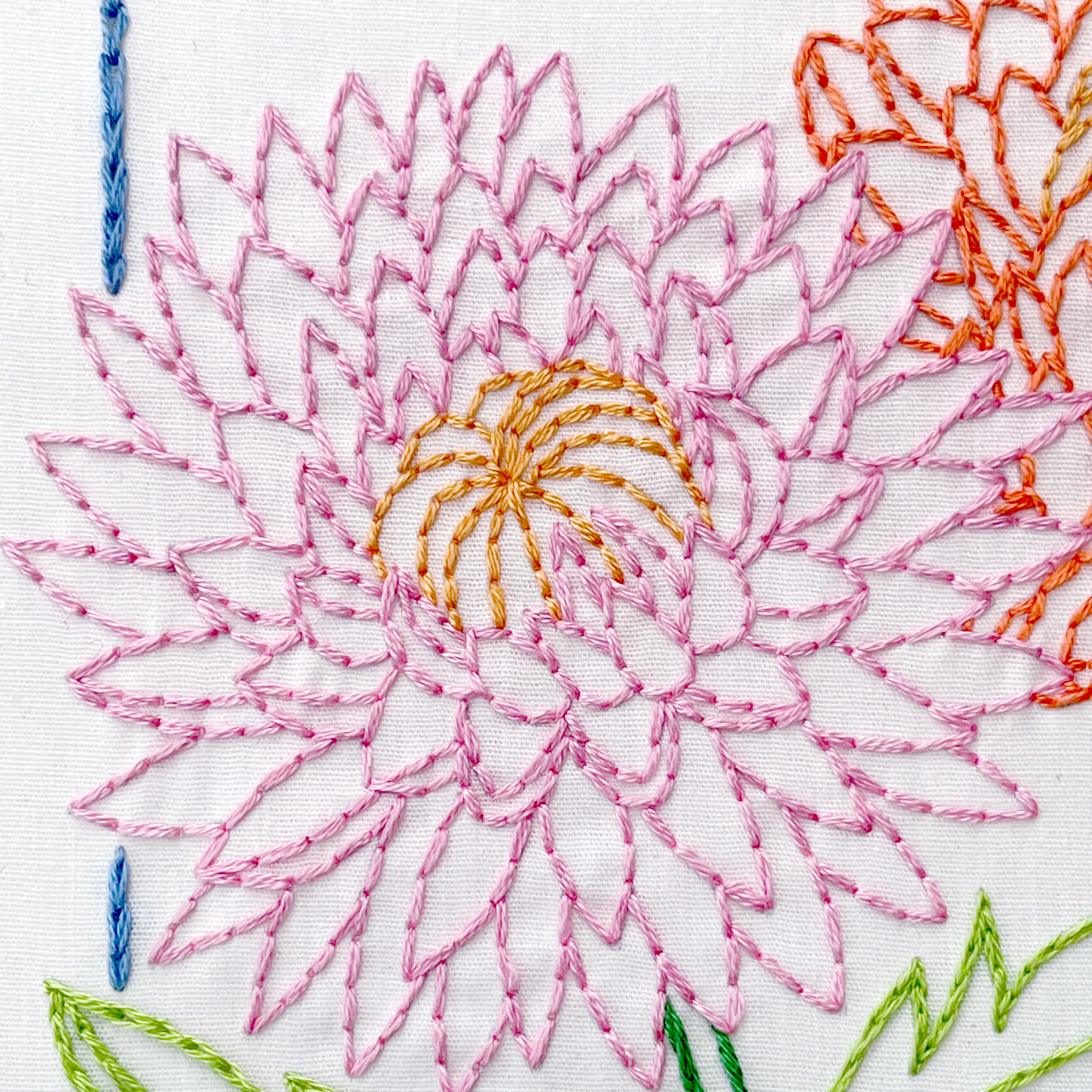 Close up of pink embroidered chrysanthemum flower in backstitch