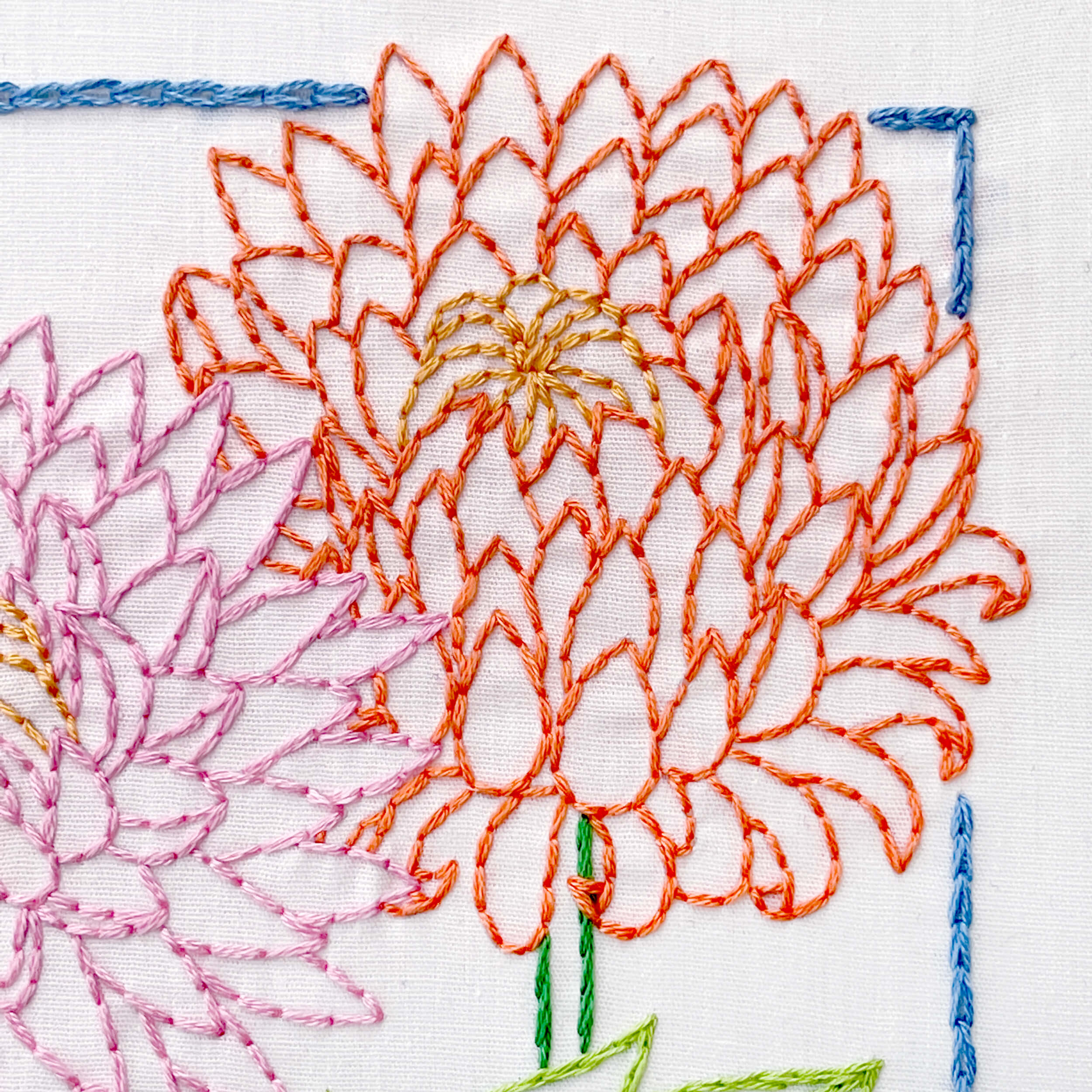 Close up of November Chrysanthemum flower in orange with blue chain stitch outline