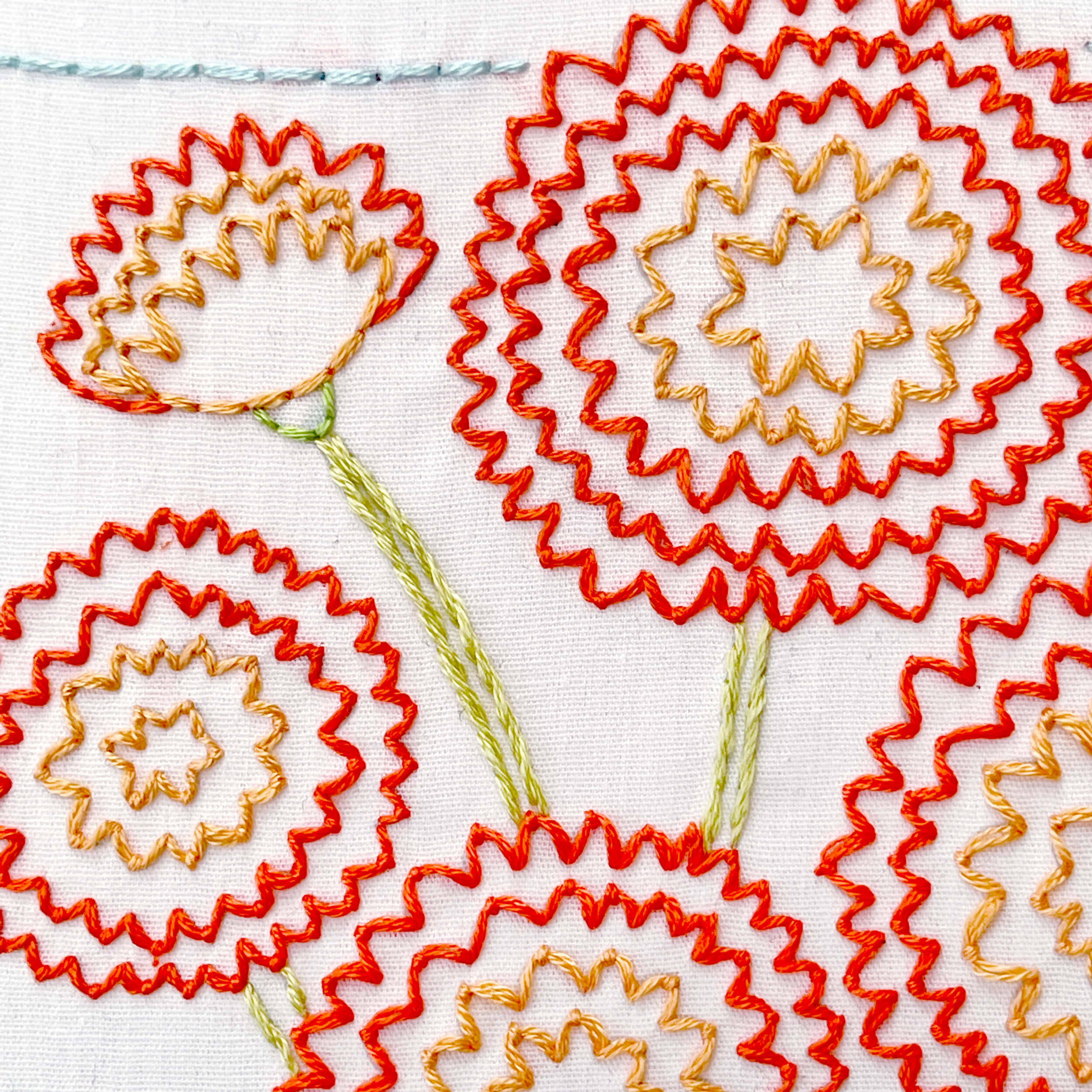 Close up of fly stitch embroidery in oranges