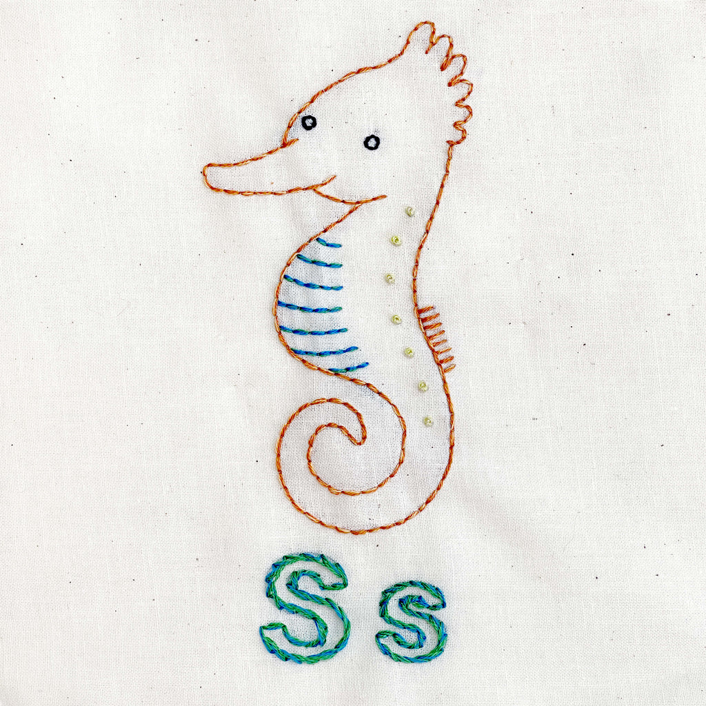 Seahorse embroidery in browns and blues with letter Ss underneath