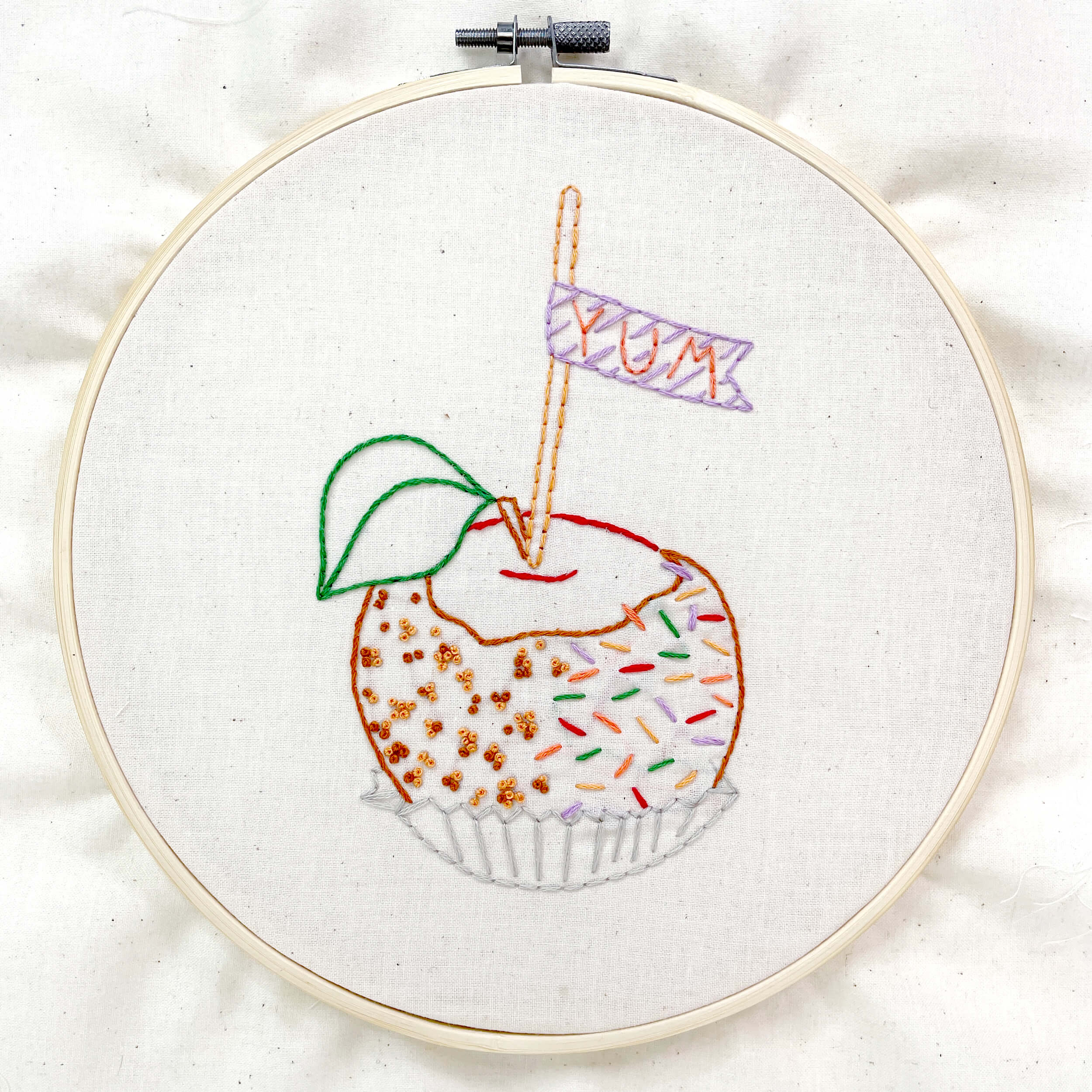 embroidery pattern of a caramel apple framed in a hoop