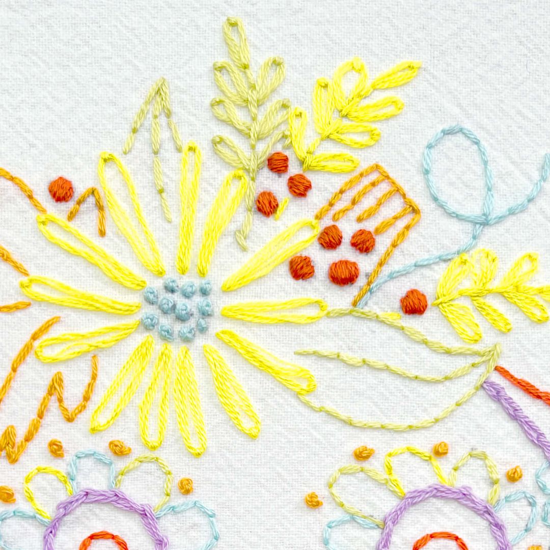 close up of yellow flower and orange satin stitched berries