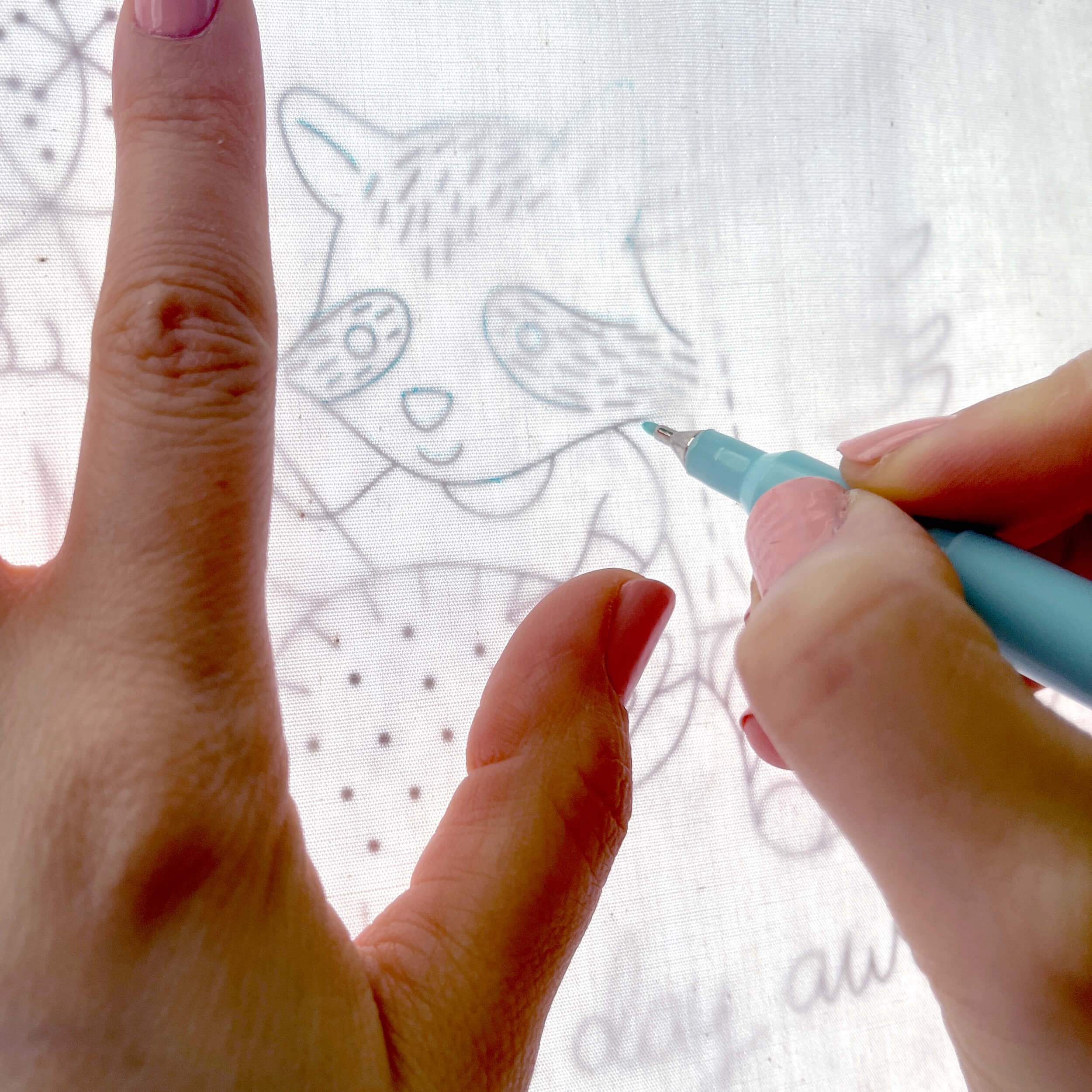 Hands tracing embroidery pattern with water erasable pen