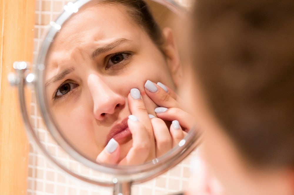 A girl watching pimple on her face