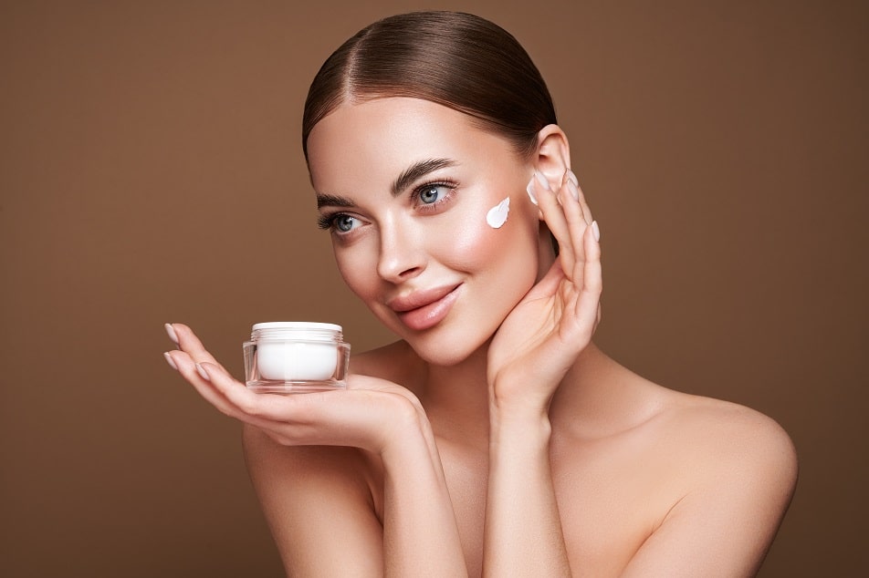 Beauty woman applying cream on her face