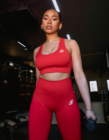 Lady in red fugafit leggings and bra top holding a dumbell