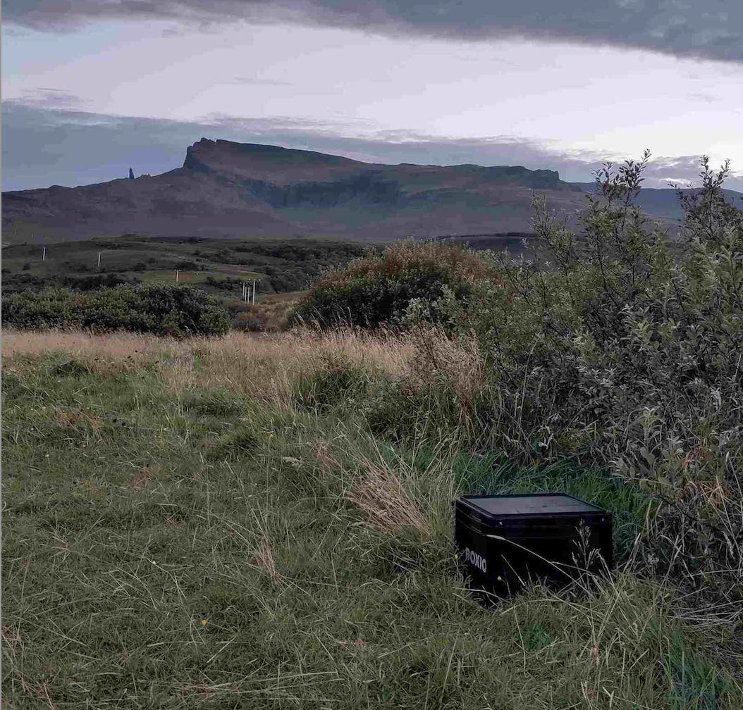 BOXIO-Toilet stands in the grass, backdrop beautiful mountain landscape 