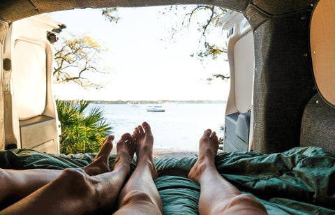 Legs of two people enjoying the view from the trunk of a camper van
