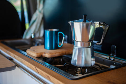 Bialetti ovenkoffiezetapparaat en kopje, op een gasfornuis van een bestelwagen