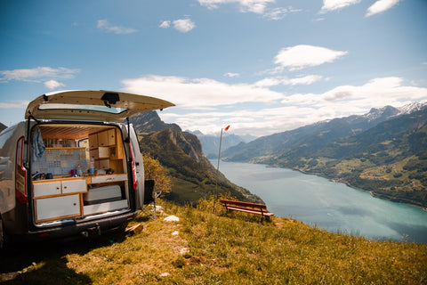 Camping-Van steht mit offenem Kofferraum in den Bergen