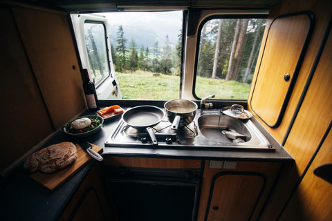 Kitchen in the trunk of a campervan with a stove and pots