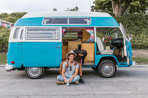 Casal sentado em frente a uma autocaravana azul ampliada e decorada