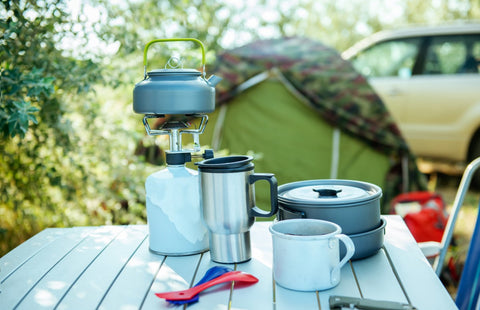 Camping stove, pots and cutlery on a camping table